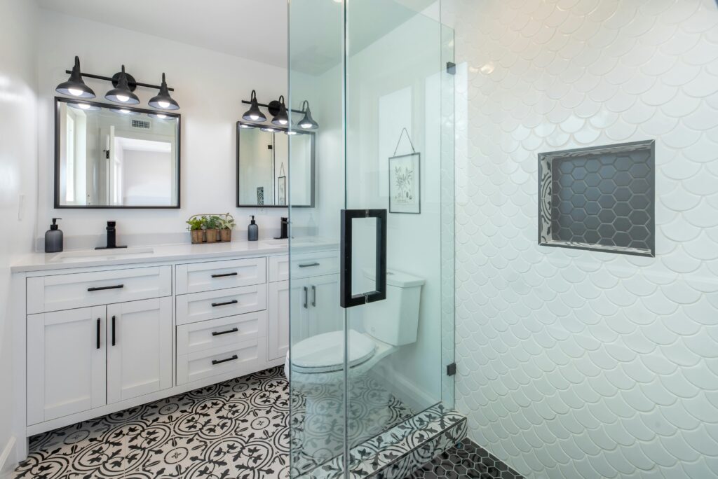 Elegant white bathroom with glass shower and stylish patterned floor.